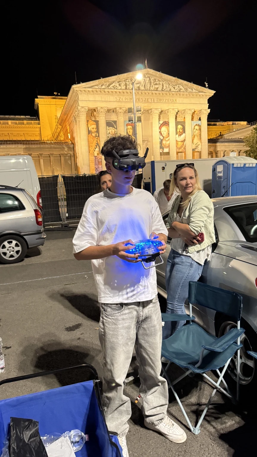 FPV pilóta éjszakai rendezvényhelyszínen videós drónművelet közben